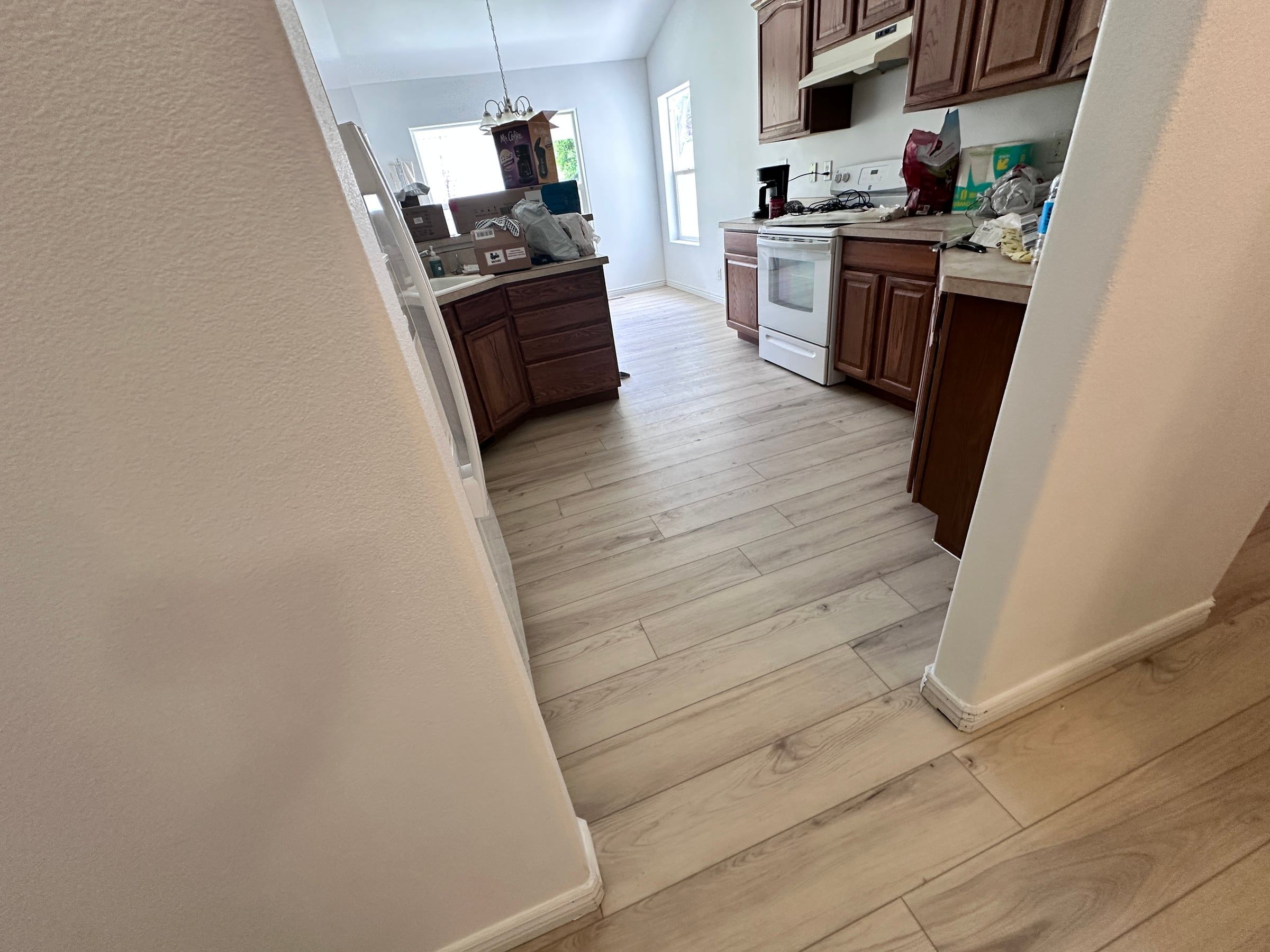 Light luxury vinyl plank leading into a kitchen