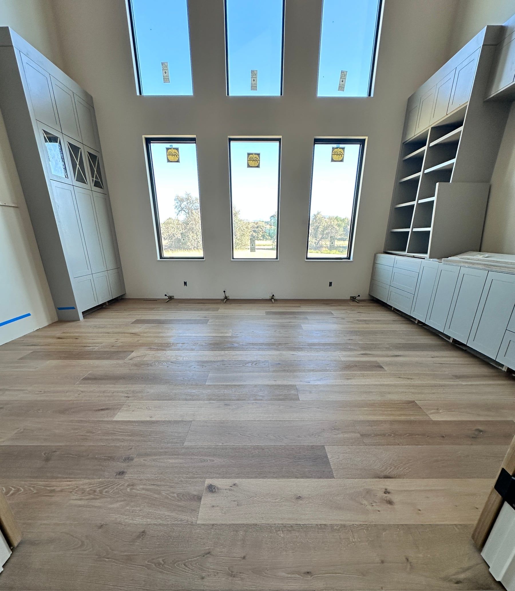 Wide-plank hardwood floor in a great room with tall windows
